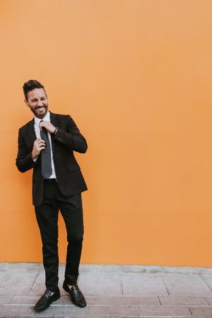 Adult stylish man in costume near orange wall