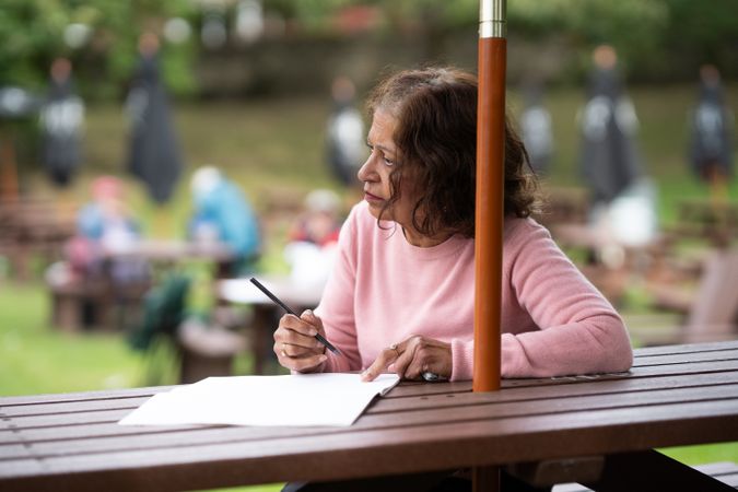 Mature woman drawing on park bench