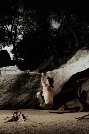 Man practicing rock climbing among large rocks in a forest
