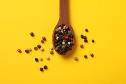 Top view of wooden spoon with whole peppercorns