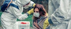 Doctors putting protective mask on woman infected with a virus