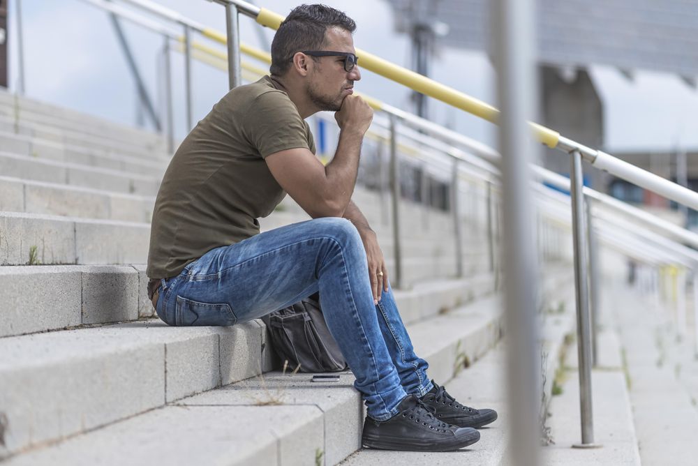 Side view of male sitting on stairs looking in the distance