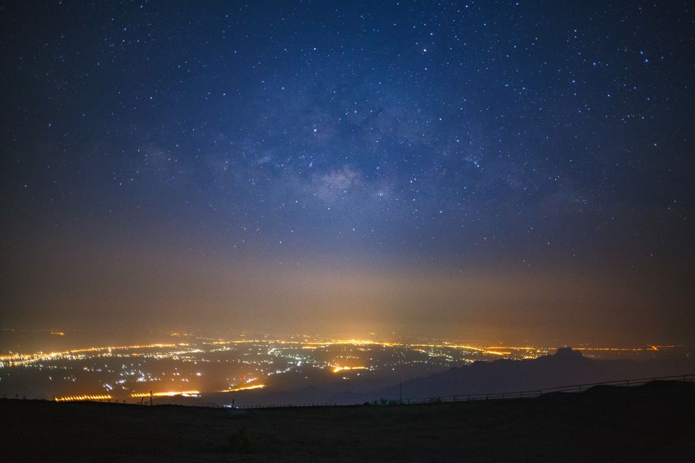 milky way galaxy and city light at Phutabberk Phetchabun in Thailand.Long exposure photograph.With grain