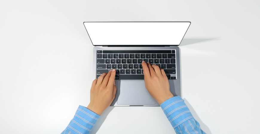 Top view of person using silver laptop with mockup screen on desk