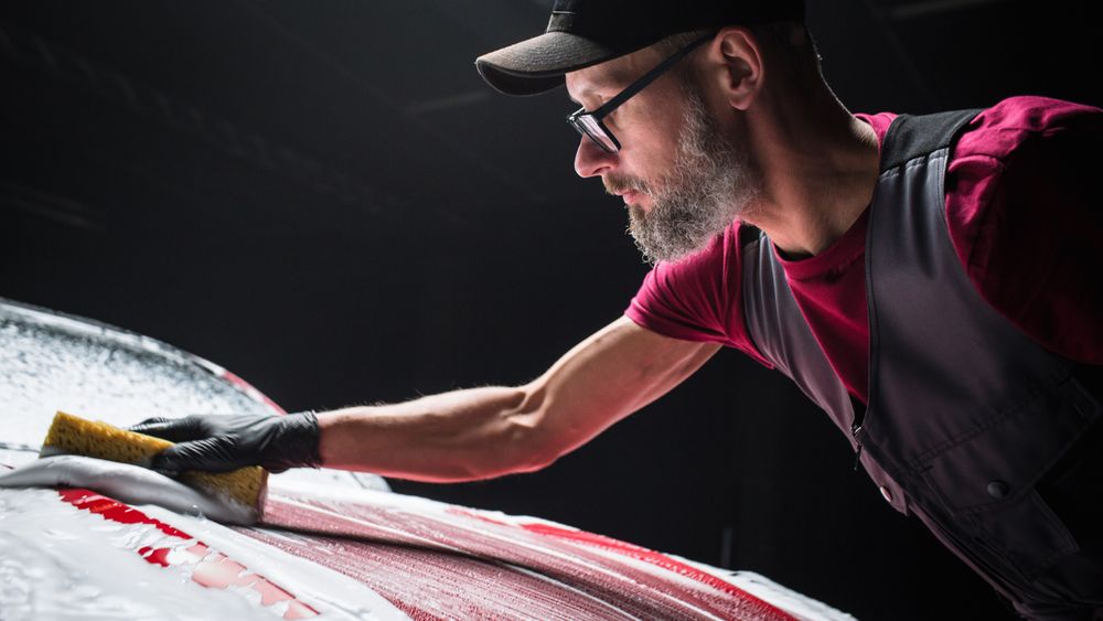 Car Ad Style Photo of a Professional Car Wash Specialist Using a Big Soft Sponge to Wash