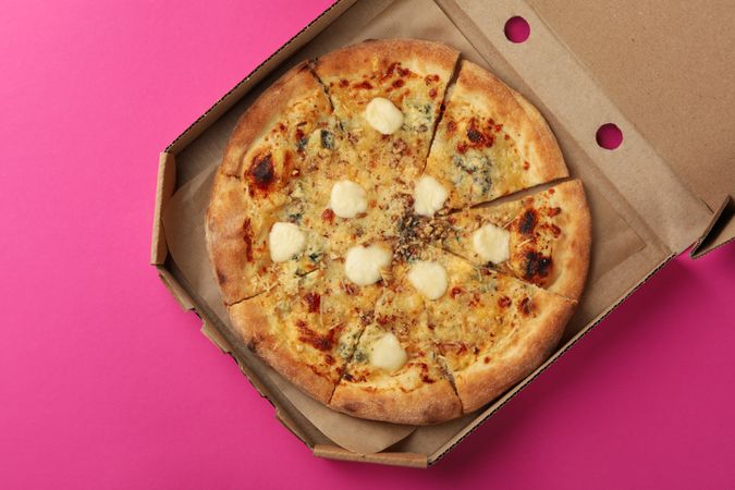 Cheese pizza in carton box on violet background