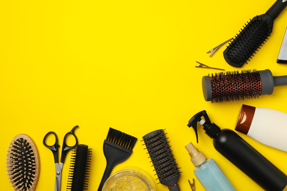 Composition with hairdresser accessories on yellow background, space for text