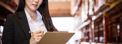Banner of business woman or manager smiling and writing on clipboard at warehouse factory