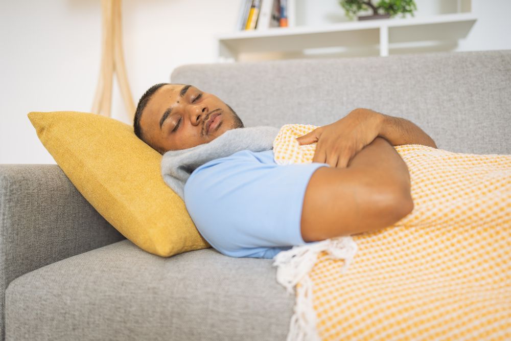 Young man with the flu napping on the living room sofa