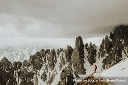 Person in red jacket standing on snow covered mountain 4B7eeb