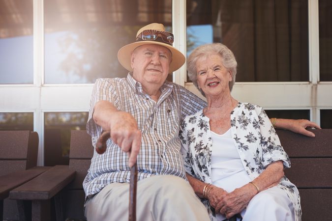 Elderly man and woman sitting relaxed on a bench outdoors