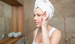 Portrait of woman plucking eyebrows with tweezers