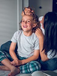 Mother doing hairstyle of little curly son