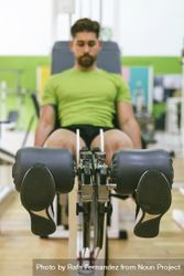 Male in green t-shirt working out quads using gym equipment bG19X5
