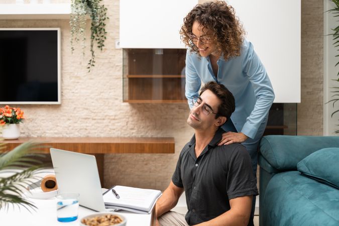 Content woman giving massage to partner at home
