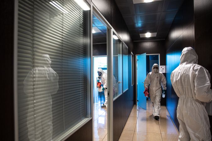 People wearing PPE sanitizing a hallway of an office during Covid-19 lockdown