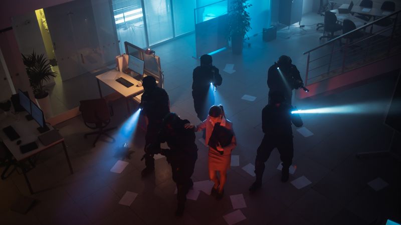 Masked Squad of Armed SWAT Police Officers Rescue a Female Hostage in a Dark Seized Office Building with Desks and Computers.