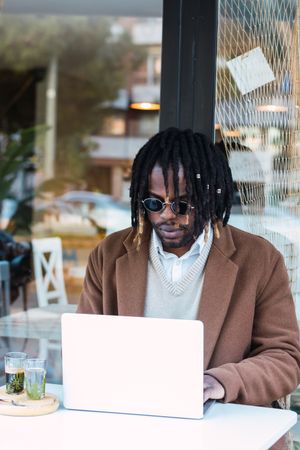 Black man browsing on laptop on restaurant terrace