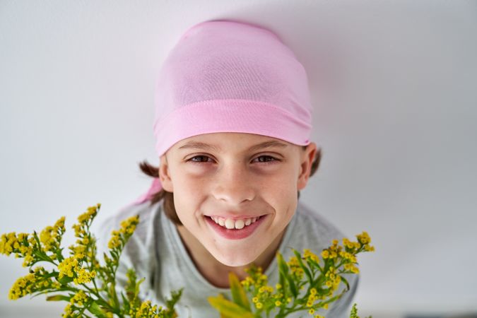 Cheerful child in pink bandana with goldenrods