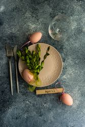 Top view of Easter table setting with branch and decorative baby pink eggs