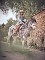 Smiling adult female equestrian sitting on gray horse