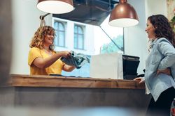 Saleswoman at shop packing purchases in shopping bag
