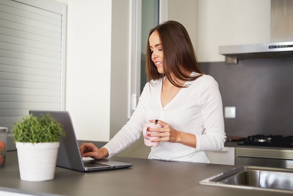 Smiling woman browsing on laptop and sitting on settee