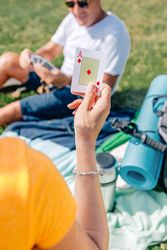 Back of woman holding up ace of diamonds card on picnic