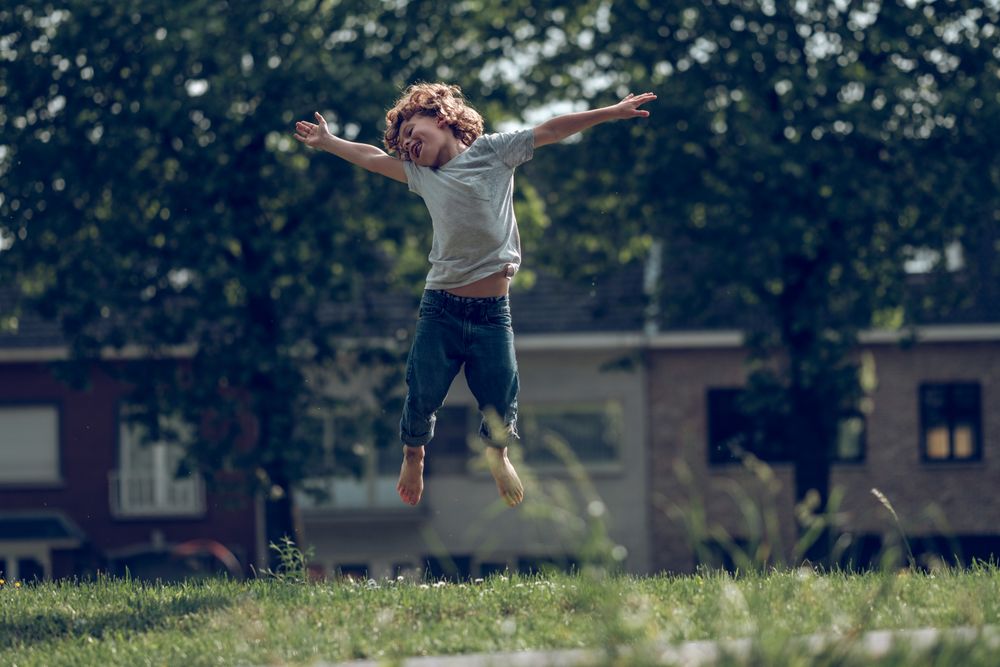 Cheerful boy jumping in meadow in countryside