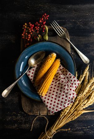 Autumn table setting with polka dot napkin, corn, wheat and berry garnish