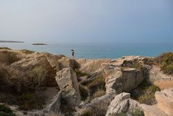 Woman running on rocky cliff near sea