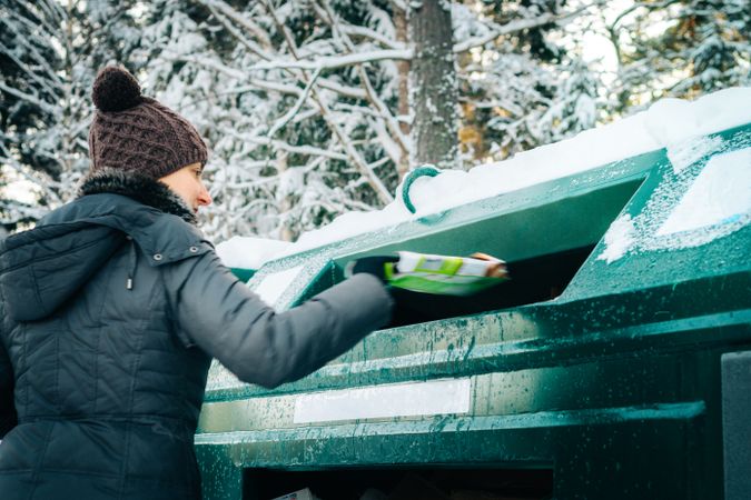 Woman throwing trash in garbage bin outdoor