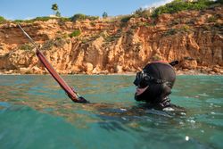 Man with speargun hunting in blue sea