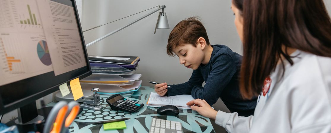Mother helping her son with his homework while teleworking