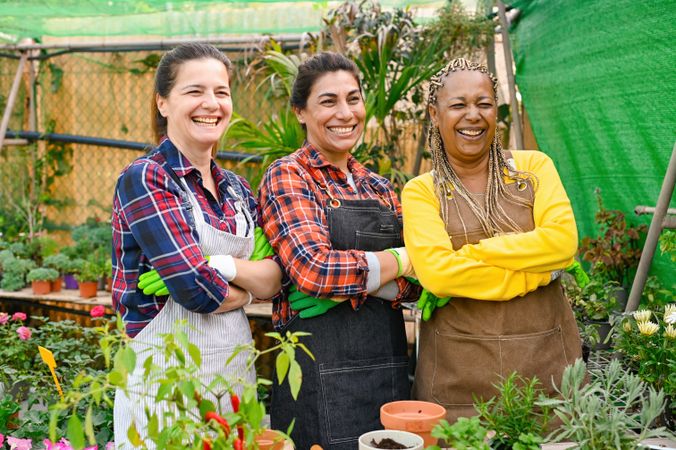 Positive multiracial farmers standing near table in garden
