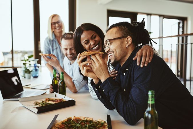 Multi-ethnic group of colleagues enjoying a pizza party in a bright modern office