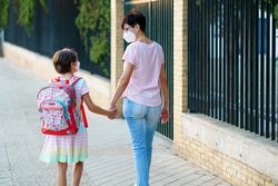 Woman and girl walking to school in face masks