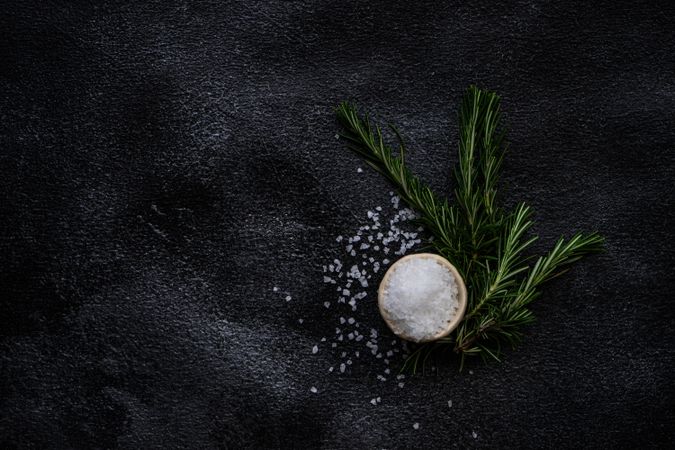 Top view of salt and rosemary on kitchen counter, vertical