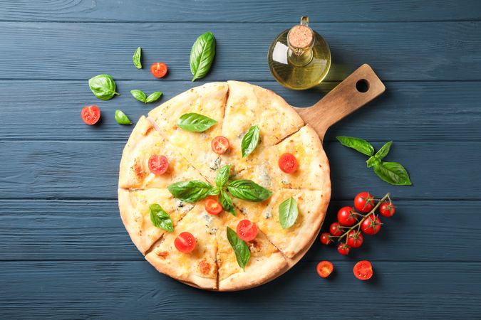 Cheese pizza, tomatoes and olive oil on wooden background, copy space