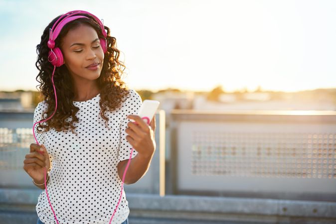 Woman in pink headphones looking at her phone
