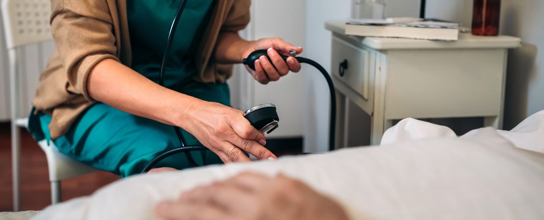 Caregiver checking blood pressure to a older woman