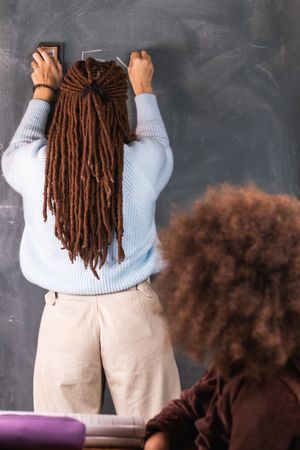 Multiracial teacher and pupil in classroom at math lesson
