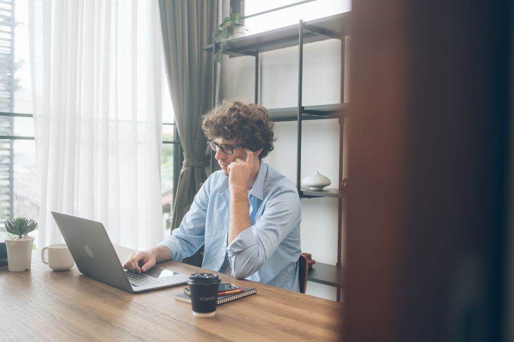 Creative freelancer serious thinking while using laptop on desk 