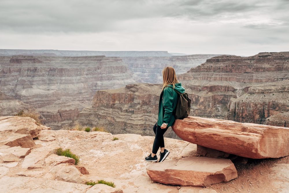 Female relaxing on cliff and admiring picturesque view