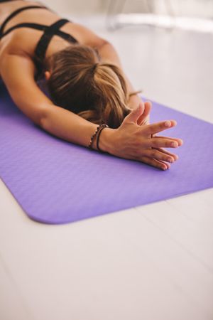 Woman doing balasana yoga at gym, with focus on hands