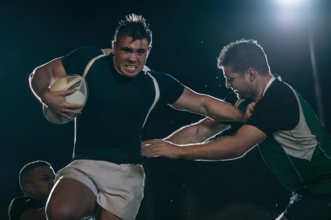 Strong rugby player tackling opponent during the game