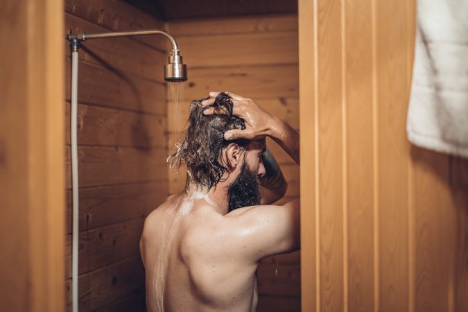 Man taking shower in wooden bathroom