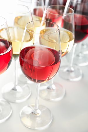 Glasses with different wine on plain background, close up