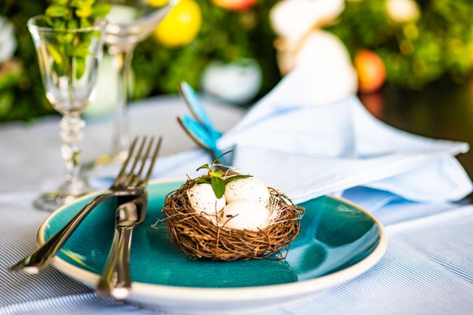 Spring table setting with bird's nest on teal plate
