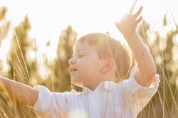 Kid in field playing with spikes at summer sunset